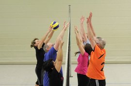Frau schlägt Volleyball übers Netz - Gegenseite versucht ihn abzuwehren